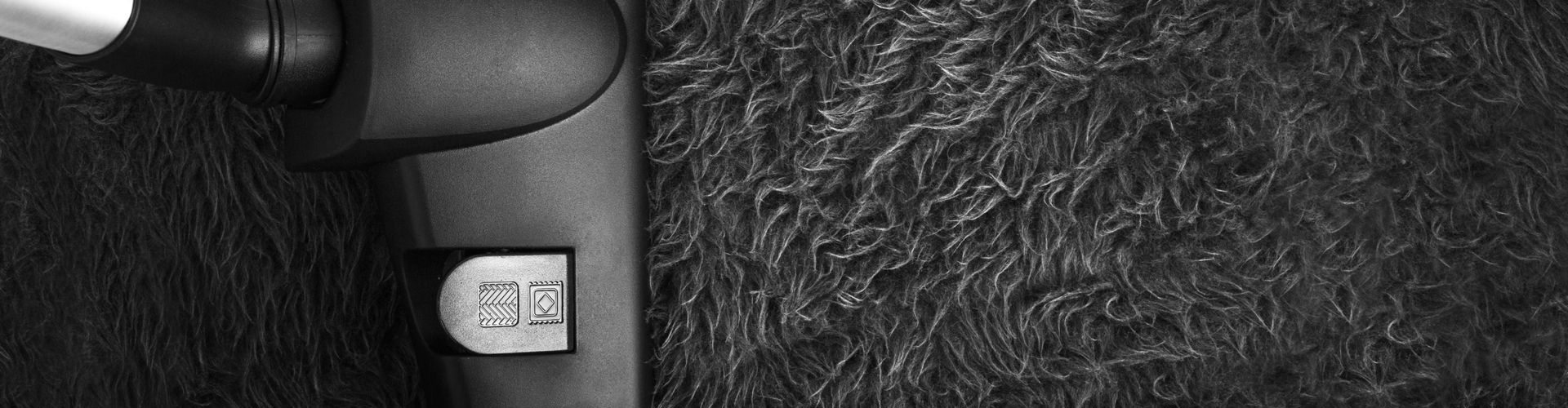 Closeup eines Staubsaugers, der einen Hochflorteppich saugt